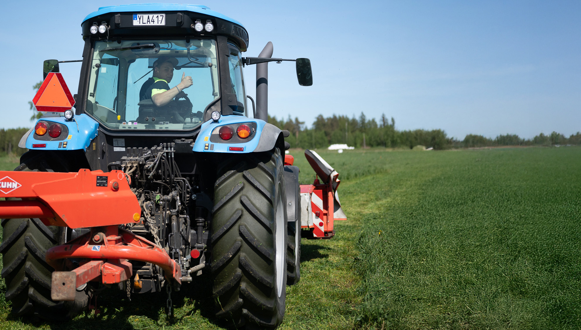 Traktor med slåtter på öppet fält
