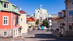 Strömstad centrum. Trähus i olika kulörer, rött, gult och beige. Längst bort i bild tornar en stor beige byggnad upp med torn och klocka på utsidan.