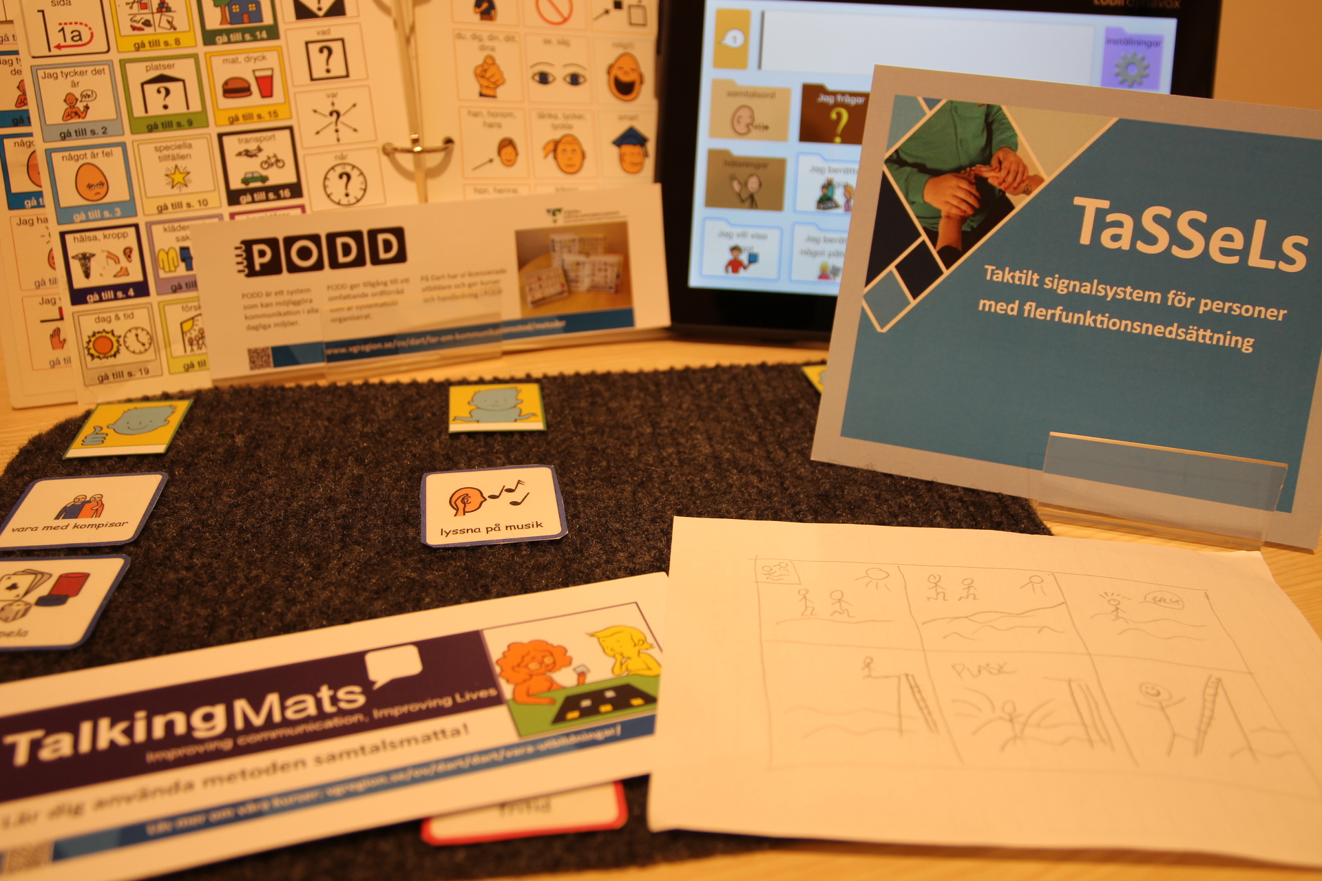 Olika broschyrer på ett bord för till exempel Talking Mats, Tassels och PODD.