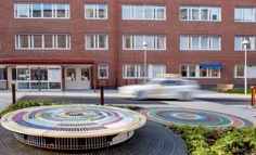 Rundlar med färgade kakelplattor. I bakgrunden en röd tegelbyggnad och en taxibil.
