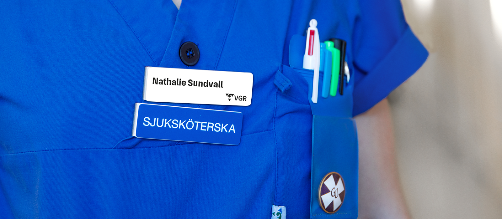 Namnskyltar på blå vård kläder