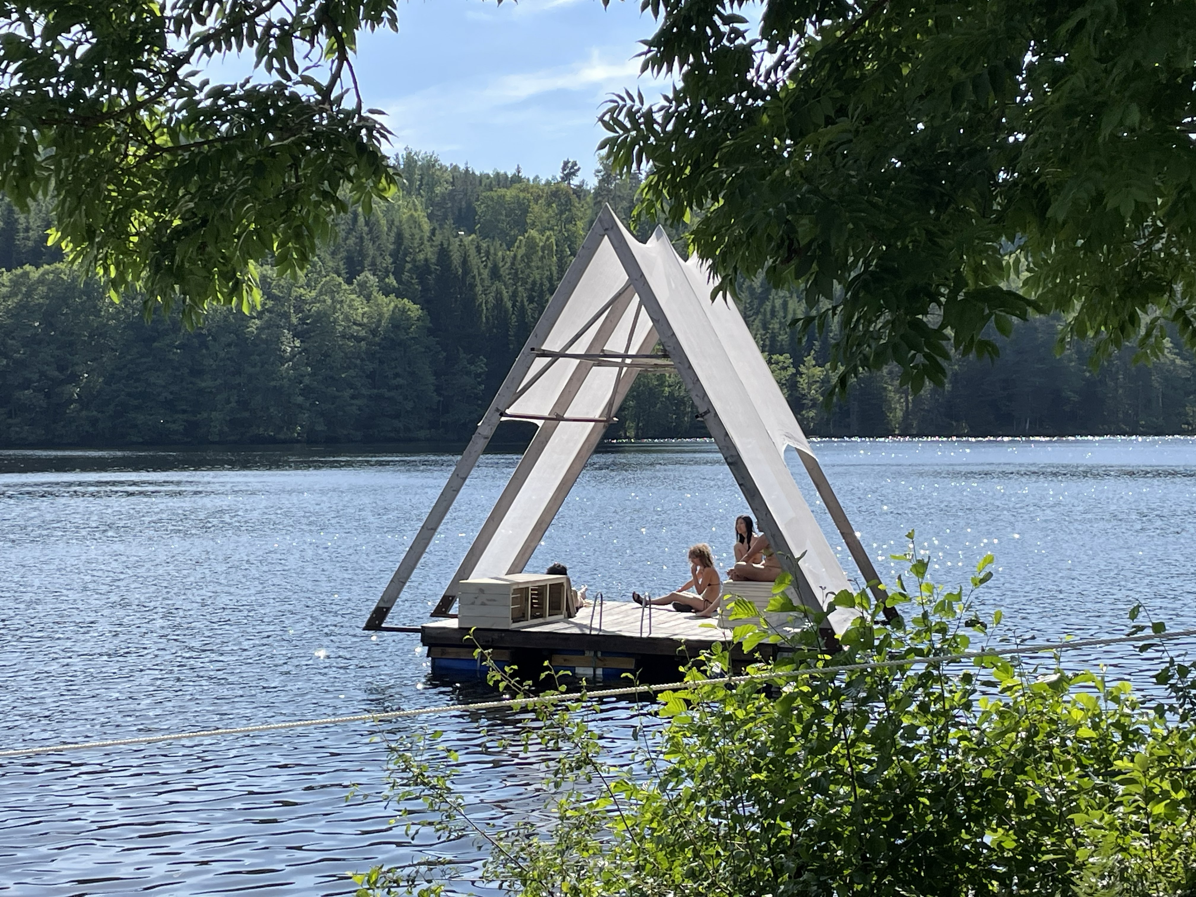 Flotte med tälttak på dalslands kanal. Fotograferad med lummig grönska i för- och bakgrunden.