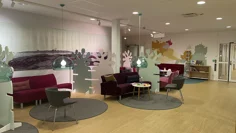 Vöntrum med träfärgat golv, röda och grå sittgrupper.