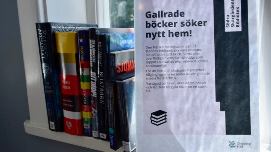 En skylt med texten "Gallrade böcker söker nytt hem!". Bredvid står ett tiotal böcker.