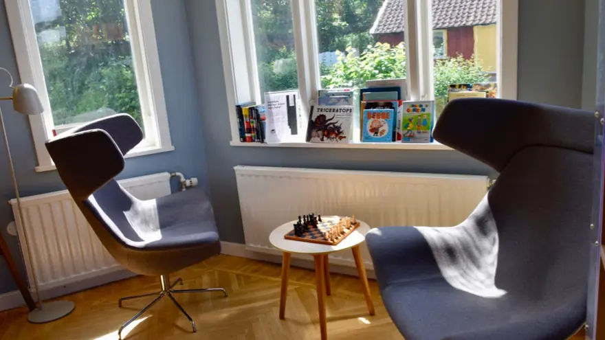 Två snurrfåtöljer står i ett burspråk. Mellan dem står ett schackspel.