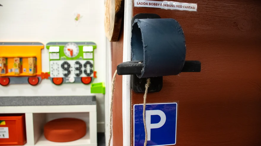 På en skylt står det "ladda Bobby bokbuss med fantasi" och där finns en tankanordning. En blå skylt visar också att det är en parkeringplats.