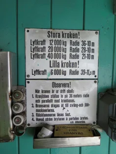 Skylt med viktangivelser och radie för stora och lilla kroken. Varningsskylt: När kranen är i drift skall 1. Kranjobben ställas in på 36 meters radie och parallellt med kranbanan. 2. Bromsarna dragas åt till sväng och jibb-maskinerna. 3. Rälsklammerna låsas fast. 4. Huvud ström brytaren à portalen brytes.
