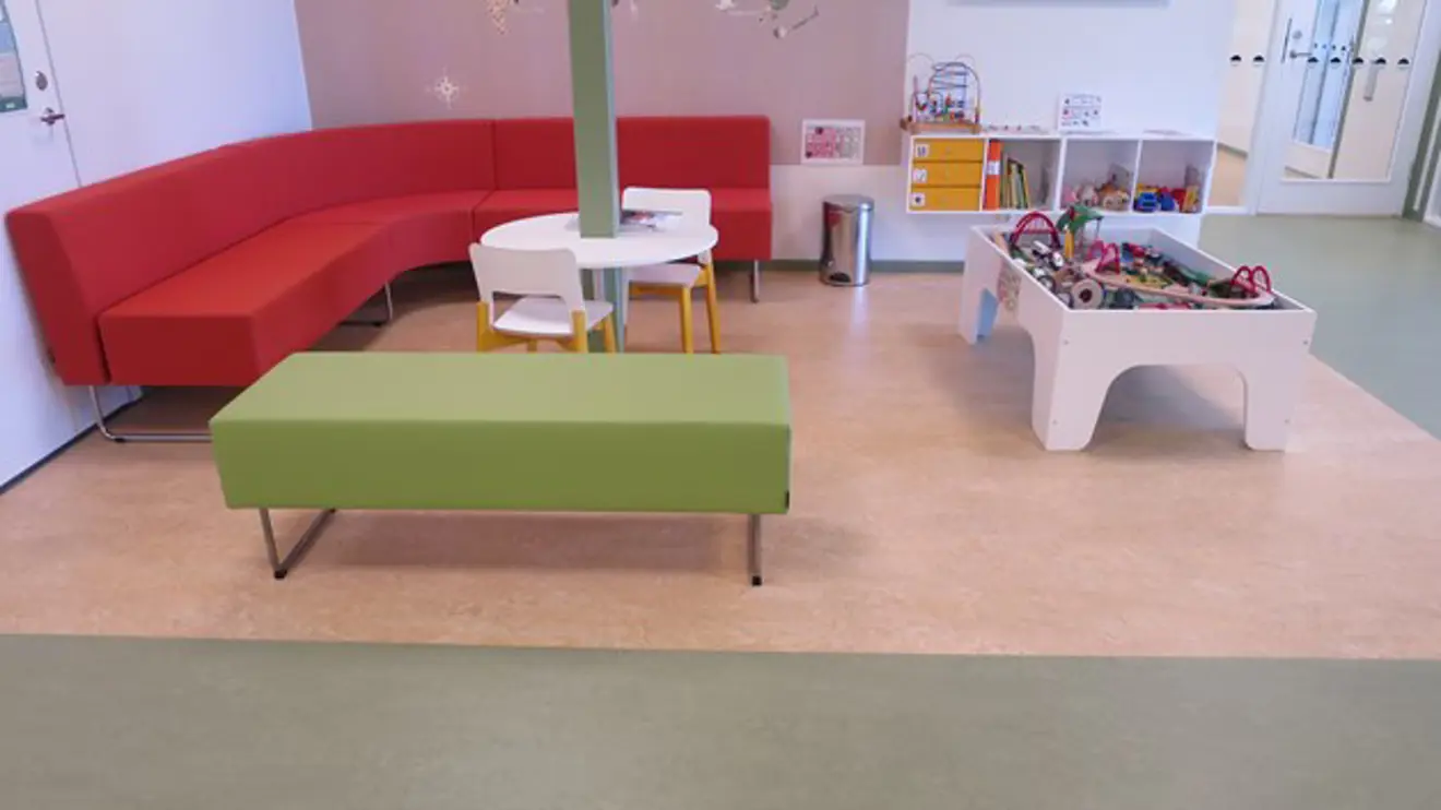 Väntrum med en röd soffa och leksaker